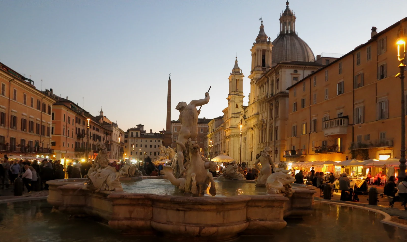 Piazza Navona na blue hour, com uma das fontes em primeiro plano e Sant&rsquo;Agnese ao fundo. Essa é uma boa referência do cl
