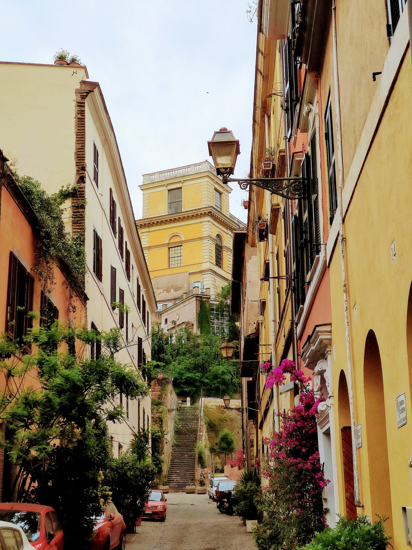 Uma rua típica de Trastevere durante o dia, estreita, colorida e cheia de camadas. É esse tipo de escala urbana que faz 