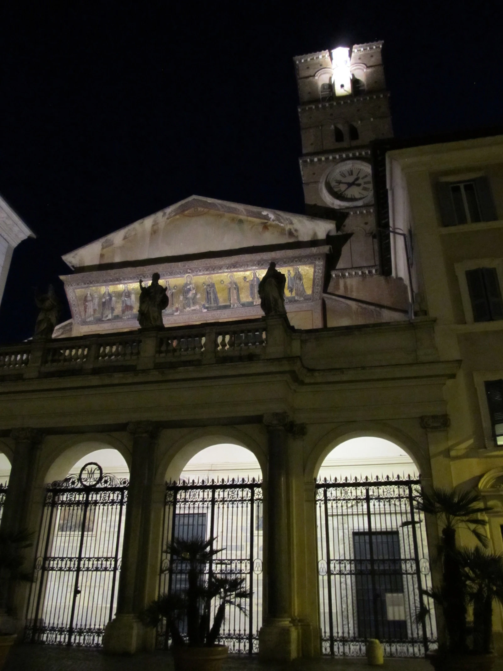Santa Maria in Trastevere iluminada à noite. A fachada fica muito mais dramática quando a praça escurece, então vale olh