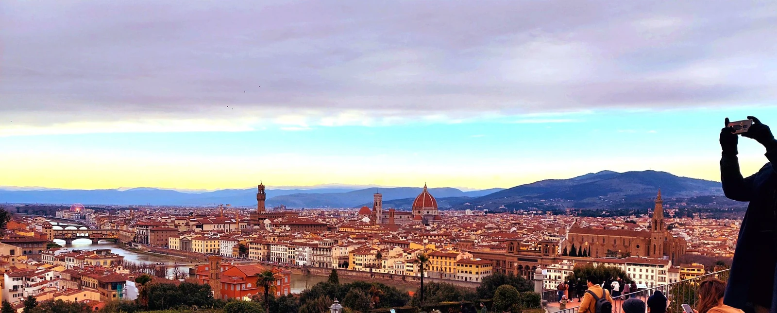 O mirante com gente ocupando a borda e fotografando a cidade. Esta é uma imagem importante porque mostra a experiência r