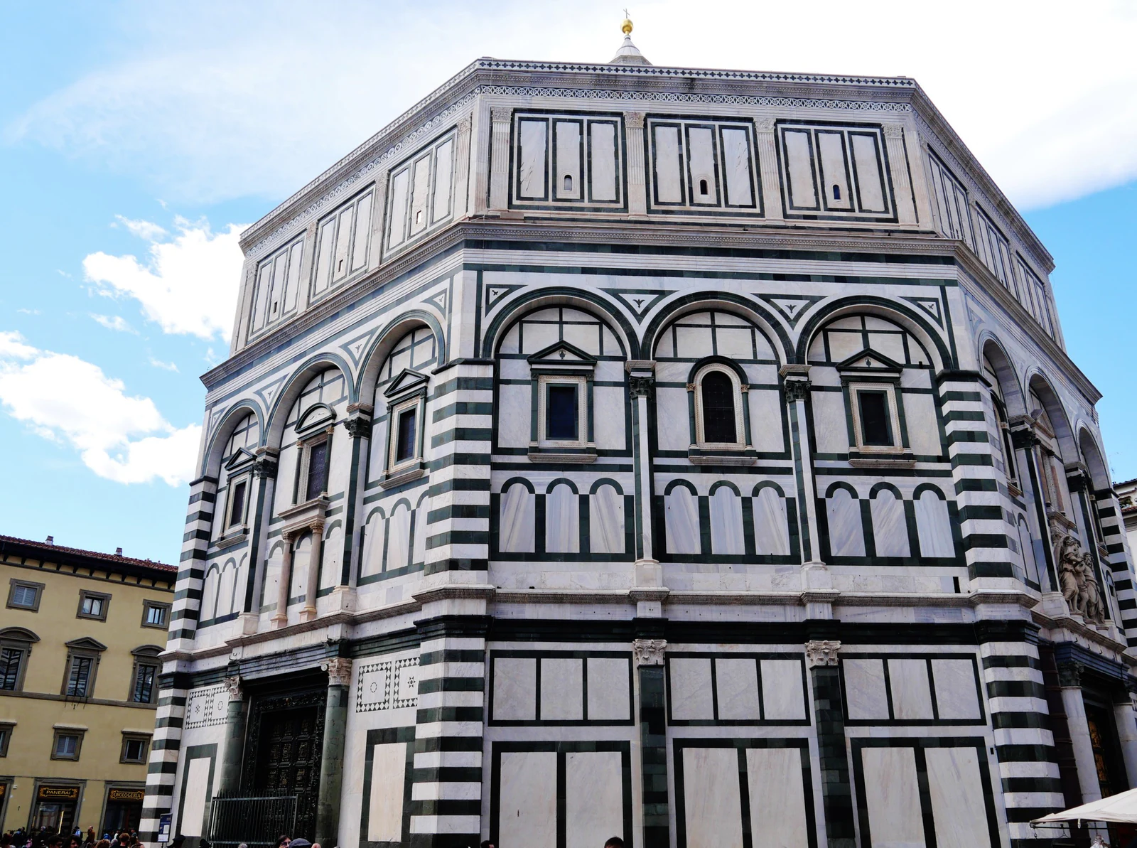O Batistério de San Giovanni inteiro, visto de fora. A forma octogonal e o desenho geométrico de mármore verde e branco 