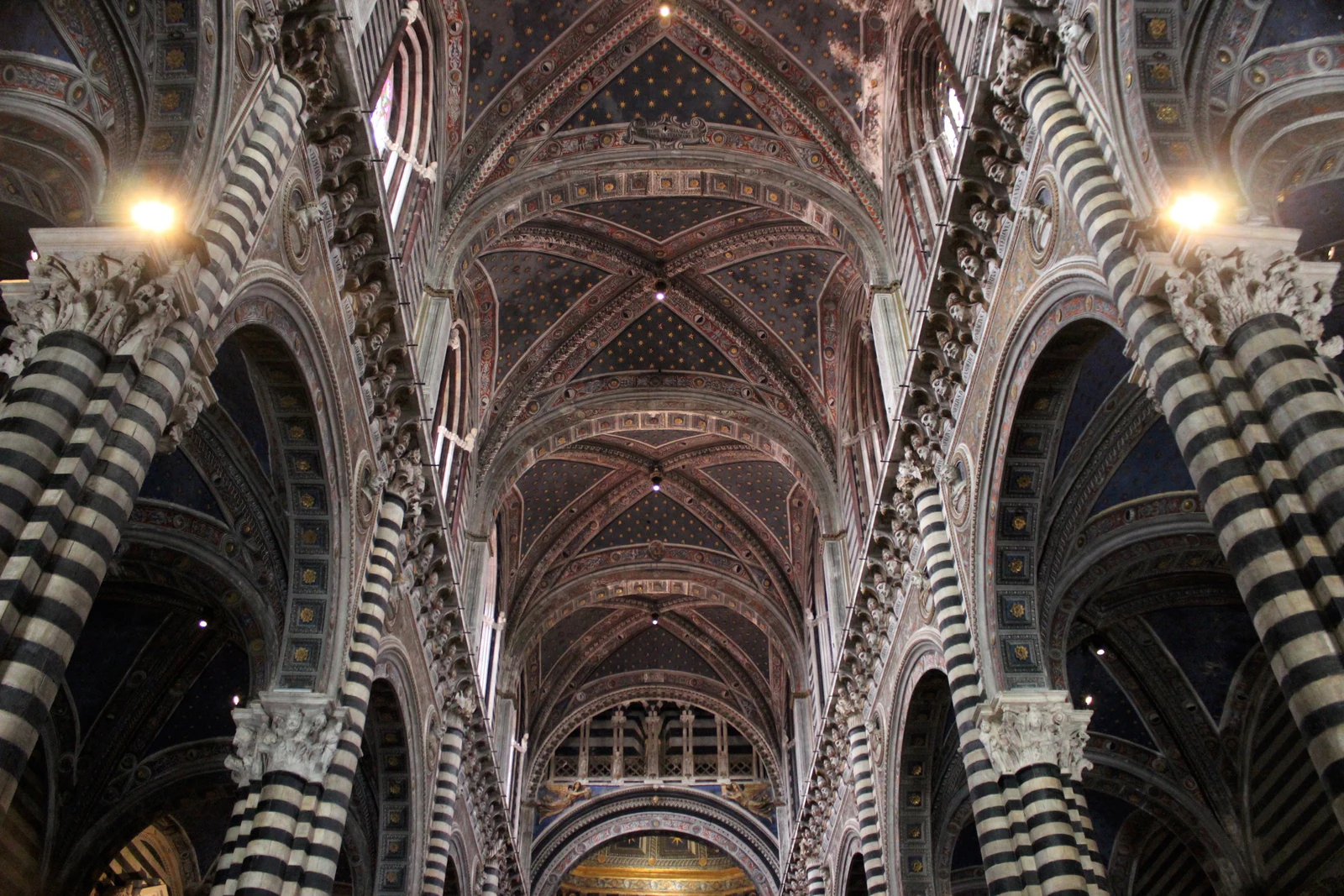 A nave do Duomo vista em perspectiva. As faixas horizontais de mármore preto e branco criam uma sensação visual completa