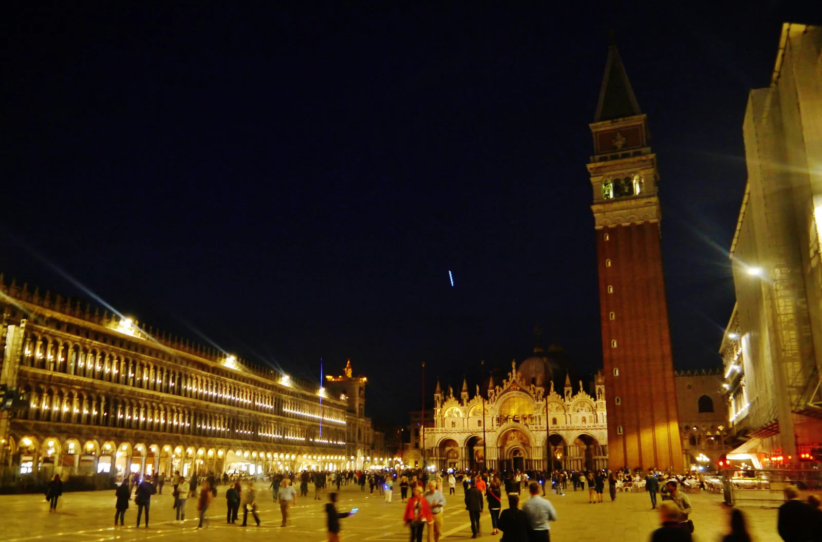 Campanile, basílica e Procuratie no mesmo quadro, com gente ainda circulando pela praça. Esta foto é útil porque mostra 
