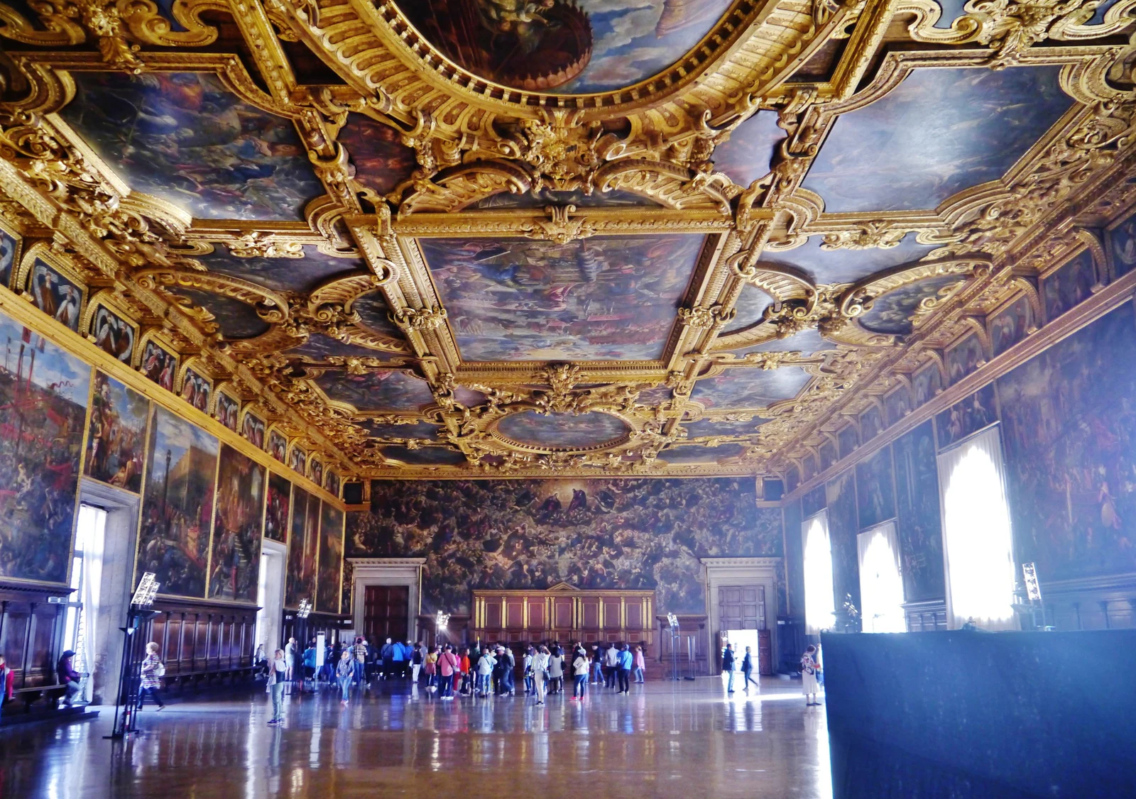 A Sala del Maggior Consiglio em grande-angular, com visitantes fornecendo a escala que nenhuma descrição consegue dar. O salão mede cerca de 53 por 25 metros e podia receber de 1.200 a 2.000 patrícios; teto, paredes e piso trabalham juntos para fazer a República parecer inevitável, estável e monumental.