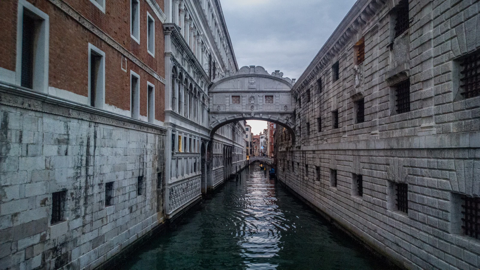A Ponte dos Suspiros sobre o Rio di Palazzo, ligando as salas judiciais às Prigioni Nuove. Vista daqui, ela parece um objeto romântico isolado; durante a visita, o que importa é perceber que existem dois corredores fechados e que a ponte era infraestrutura de circulação penal, não cenário construído para lendas de amor.
