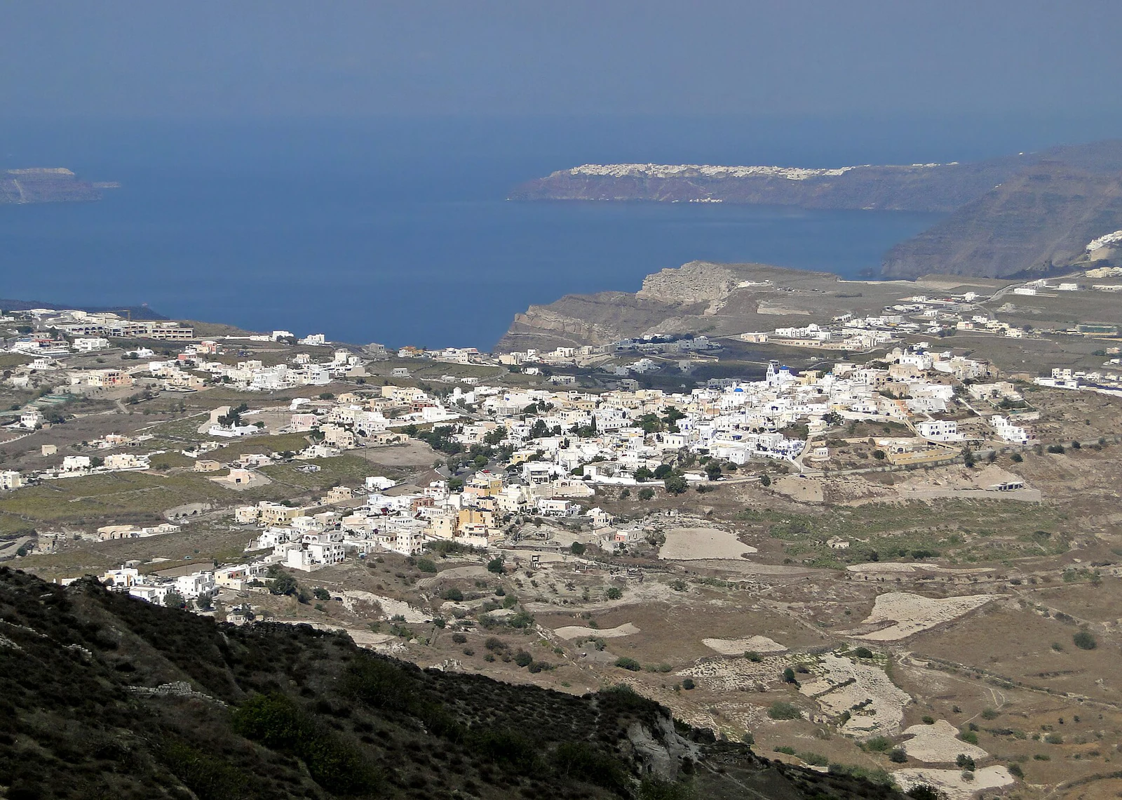 Vista de longe, Pyrgos se organiza como uma colina construída, cercada por campos e povoamento disperso.